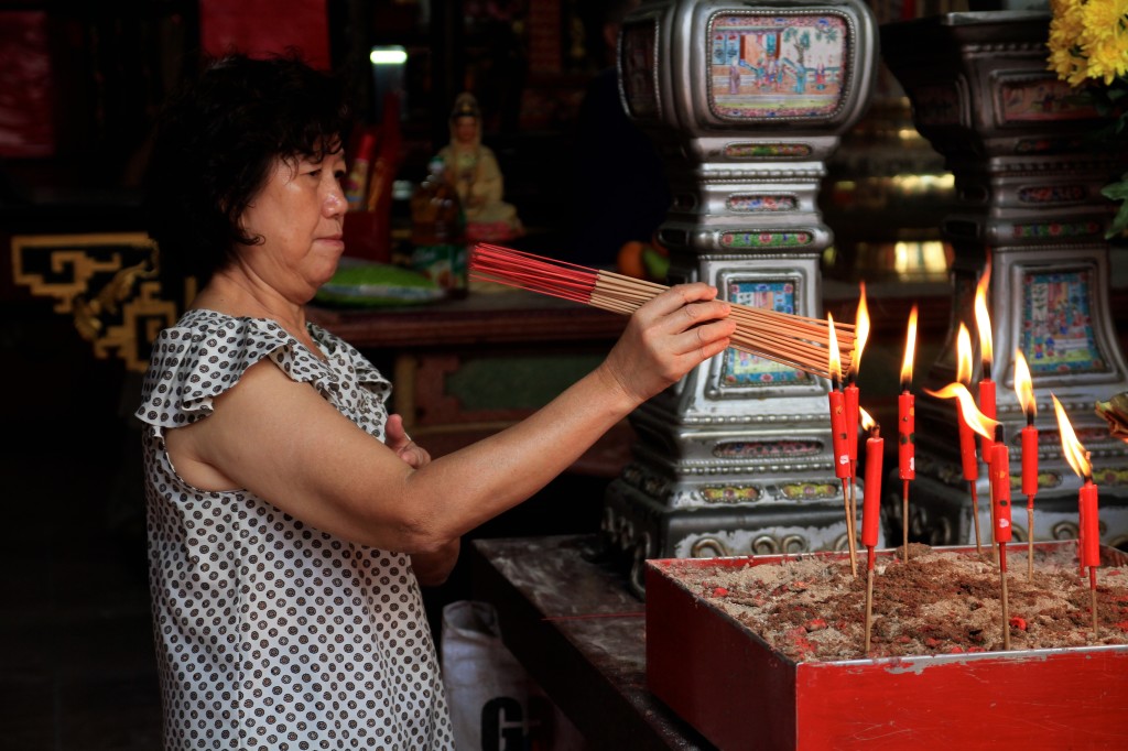 Mulher acendendo velas em um templo taoista 