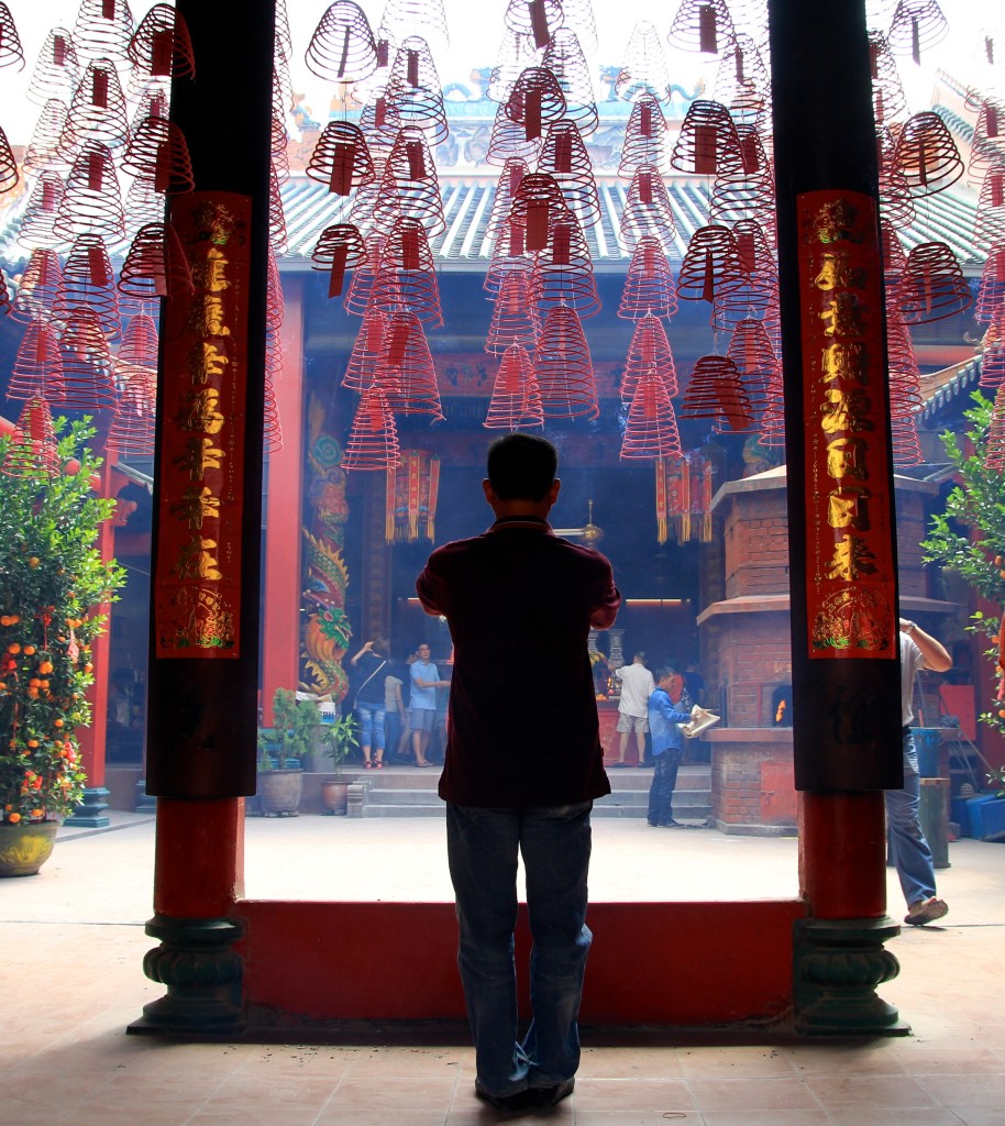 Homem reza em frente a um templo taoista em Kuala Lumpur