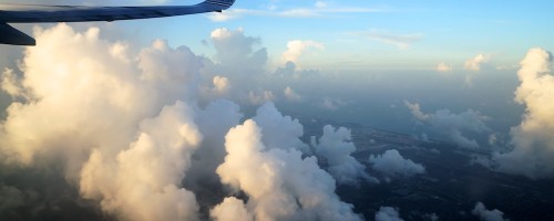 Da janela de um avião, a vista para as nuvens e o mar ao entardecer