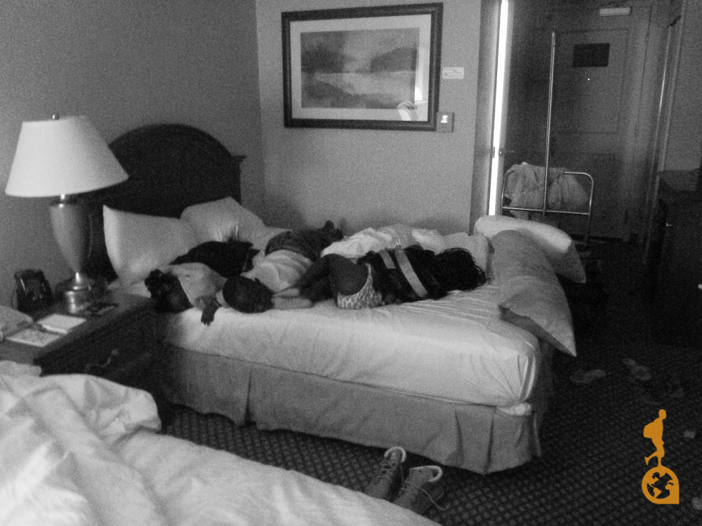 As crianças africanas na cama do hotel em Nova Iorque